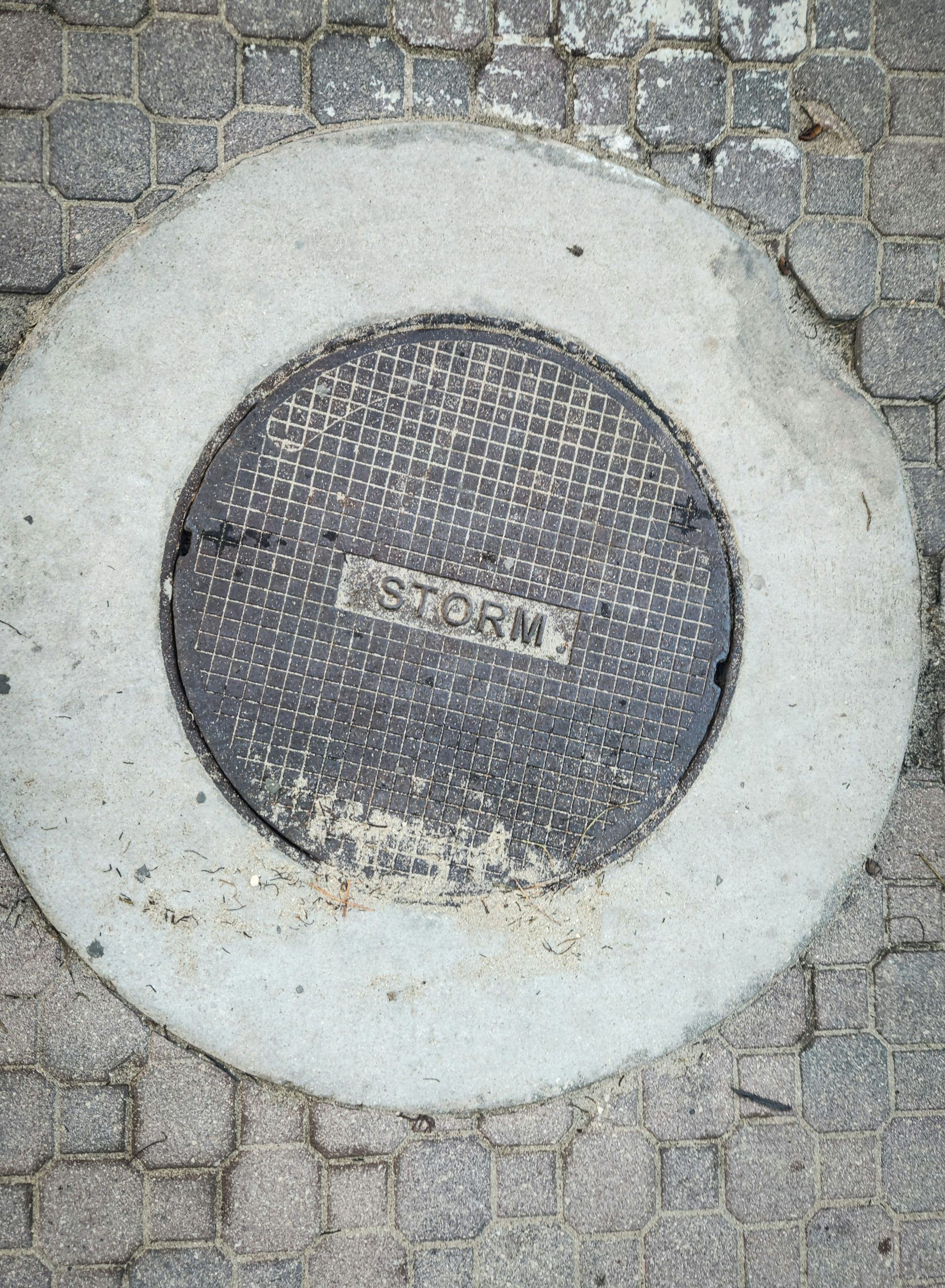 A manhole cover on a brick sidewalk